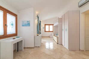 Une pièce spacieuse avec une console blanche, une fenêtre avec des rideaux, une porte en bois et un sol carrelé de couleur claire.