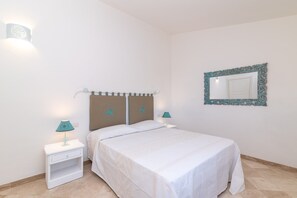Une chambre à coucher comprenant un lit, des tables de chevet, des lampes, un miroir et un élément décoratif mural.