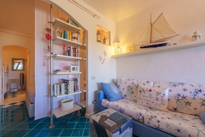 Una sala de estar con un sofá, una estantería y un modelo de barco.