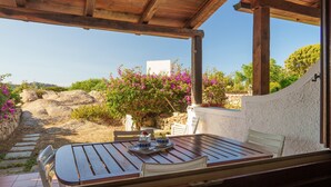 An outdoor patio with a wooden table and chairs, a stone pathway, and a view of the landscape.
