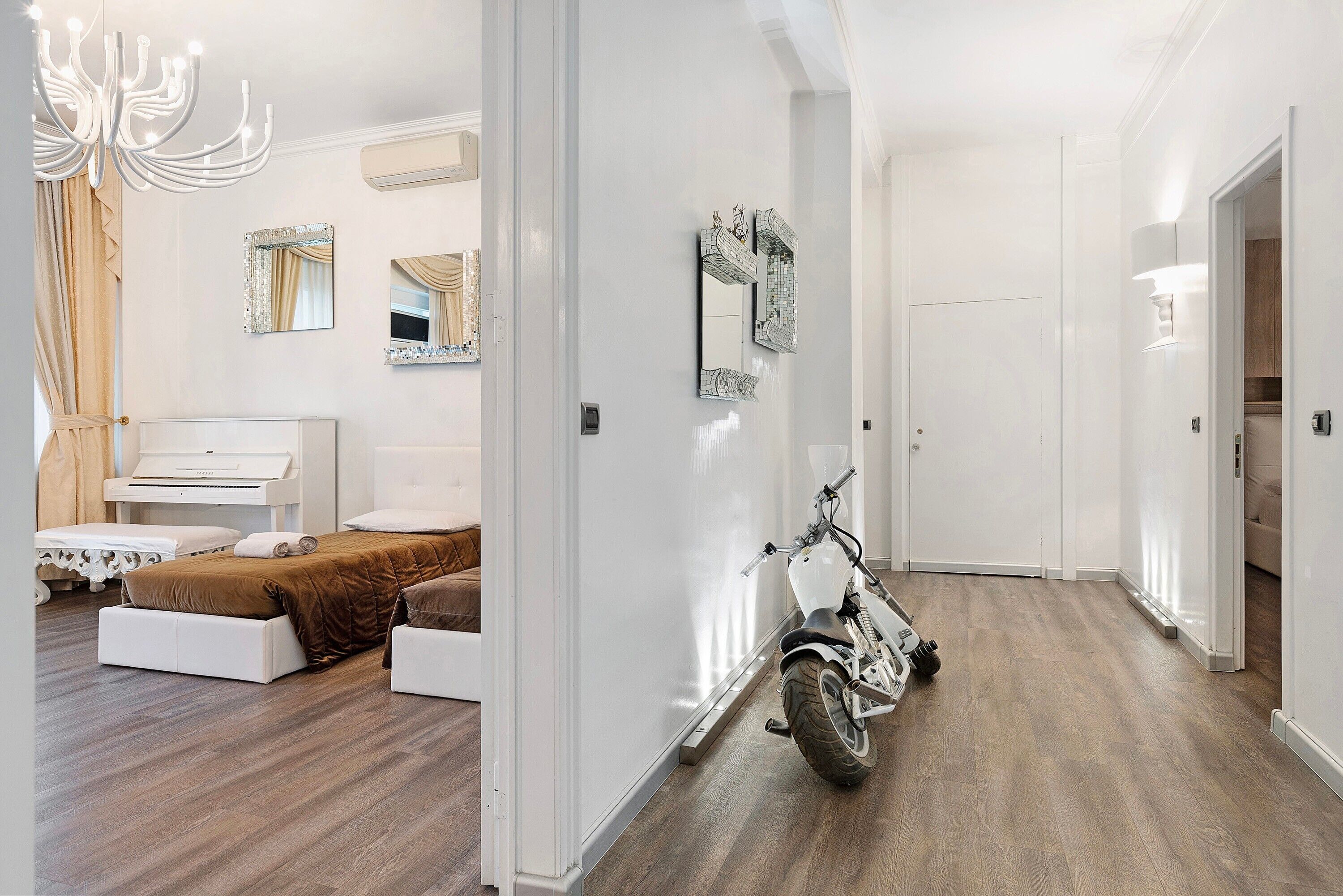 Een slaapkamer met een bed, een piano en een motorfiets in een gang.