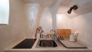 Eine Küche mit Spüle aus Edelstahl, einer schwarzen Arbeitsplatte, einem Holzschneidebrett und einem Hängearmatur.