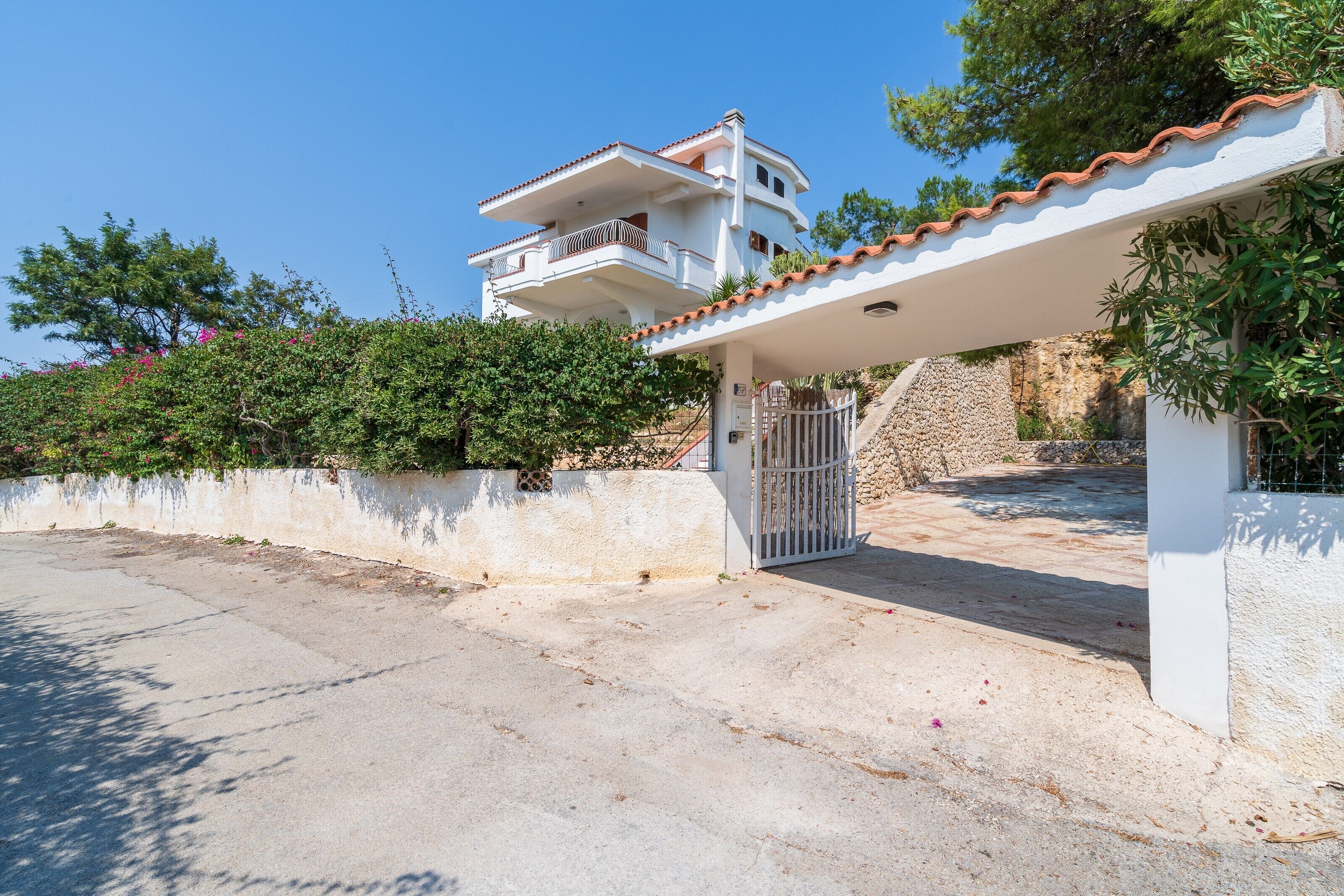 A two-story house with a balcony, a gated entrance, and a white exterior.