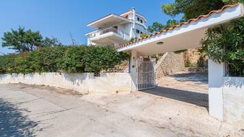 A two-story house with a balcony, a gated entrance, and a white exterior.