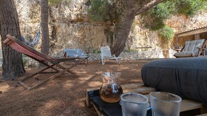 A rustic outdoor seating area with a hammock, lounge chairs, and a table with a pitcher and glasses. - Apartment "Kind of Blue" with Sea View, Wi-Fi and Air Conditioning (Siracusa)