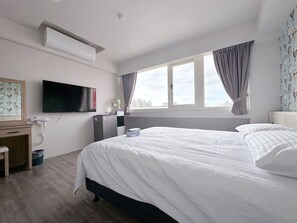 A hotel room with a bed, a desk, a television, and a window with curtains. - MENG JING HOTEL (Taoyuan City)