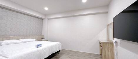 A modern bedroom with a bed, bedside tables, a wooden floor, and a large mirror.