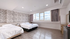 Una habitación de hotel moderna con dos camas, un ventanal con vistas a la ciudad, una pared con diseño de piedra y suelo de madera.
