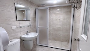 Un baño moderno con inodoro, lavamanos y ducha.