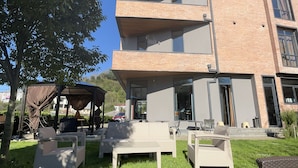 Un bâtiment moderne avec une façade en briques et de nombreux balcons. On y trouve des espaces de détente en plein air, aménagés avec des meubles en osier.
