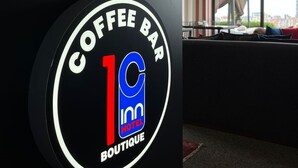 Une enseigne pour un café, avec un logo et l’inscription « Coffee Bar 1C Boutique ».