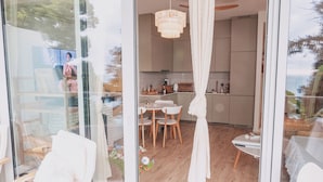 Un interior moderno con comedor, cocina y grandes ventanales con vistas al exterior.