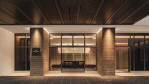 Una entrada de hotel moderna con un mostrador de recepción, una zona de estar y un techo de madera.