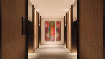 A hallway with wooden paneling, a carpeted floor, and a wall-mounted sign with room information.