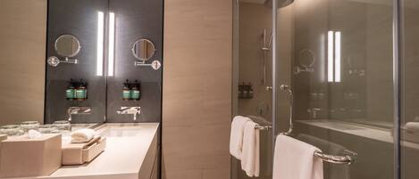 A modern bathroom with a glass-enclosed shower, a vanity with a large mirror, and neatly arranged toiletries.