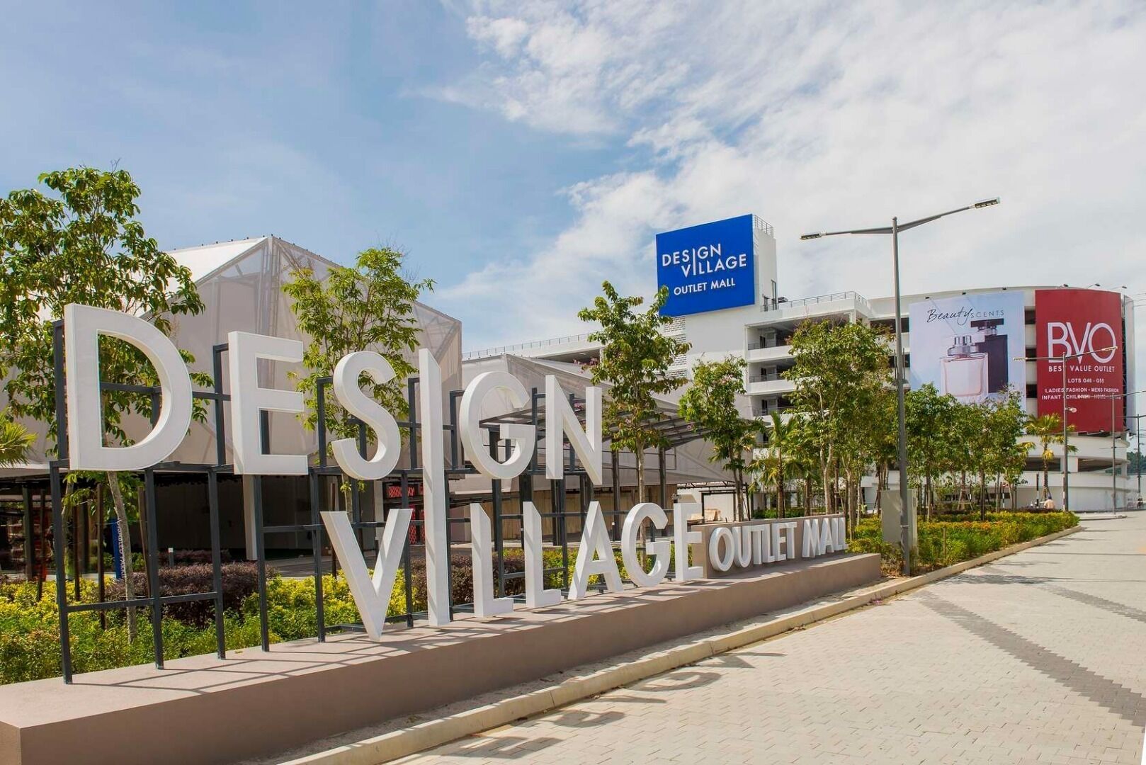 La entrada a Design Village Outlet Mall, con señalización grande y un cielo despejado.