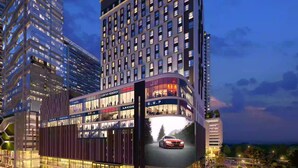Un hotel moderno con varios pisos, amplias ventanas y un anuncio llamativo de automóviles.