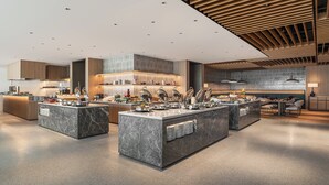 Cocina de hotel moderna con encimeras de mármol, electrodomésticos de acero inoxidable y una disposición tipo bufé.