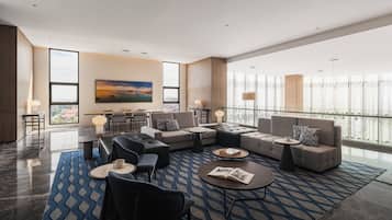 A modern lounge area with a sofa set, coffee tables, and a dining table.