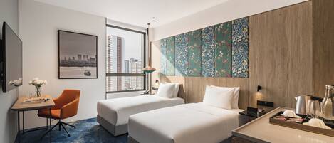 Habitación de hotel con dos camas, un escritorio con silla, vista a la ciudad y un adorno en la pared.