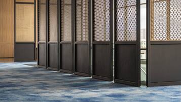 A row of traditional sliding doors with a patterned lattice design, leading to a room with a blue carpet.