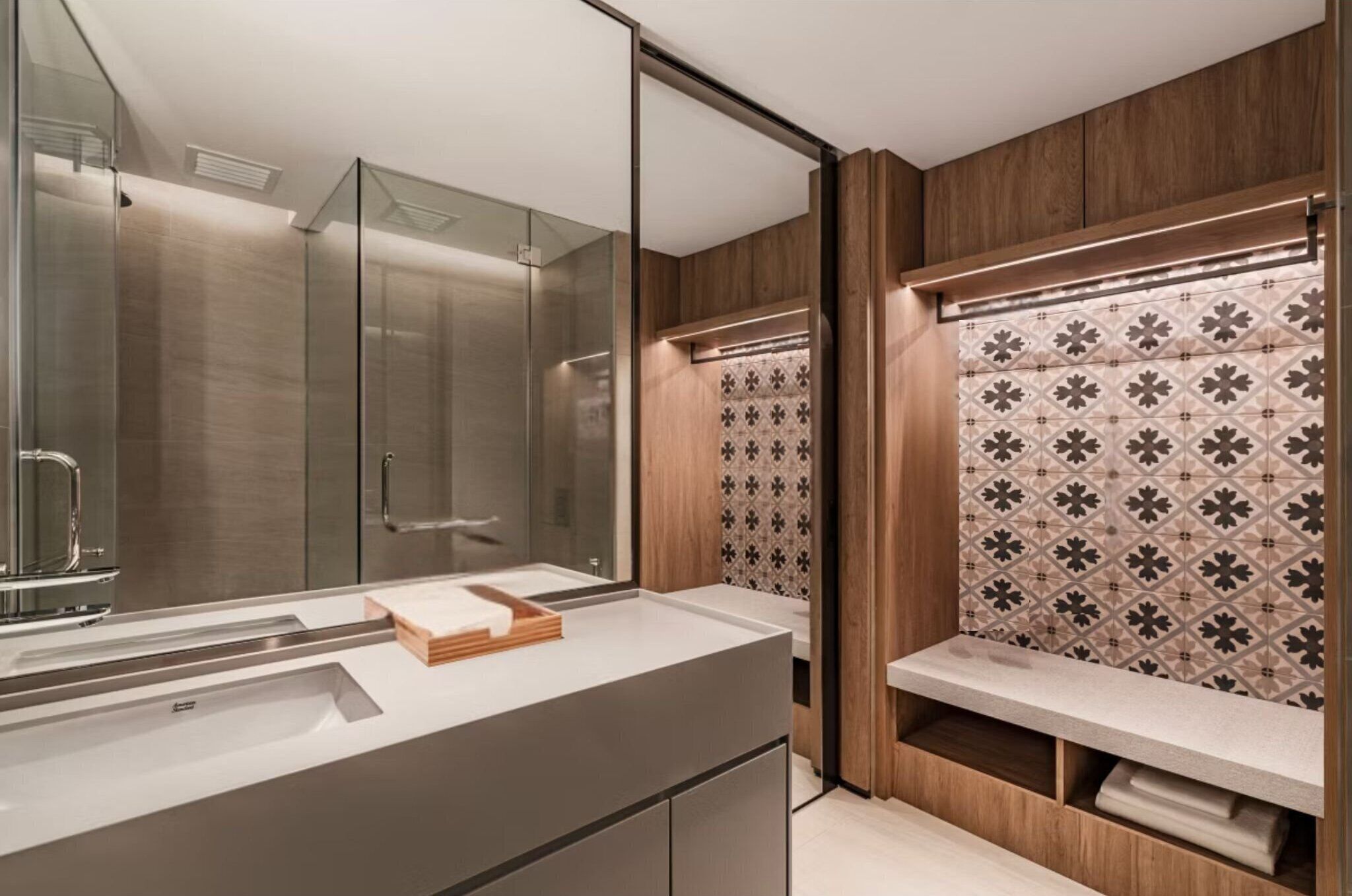 A modern bathroom with a glass shower enclosure, a large mirror, and a vanity with a patterned backsplash.