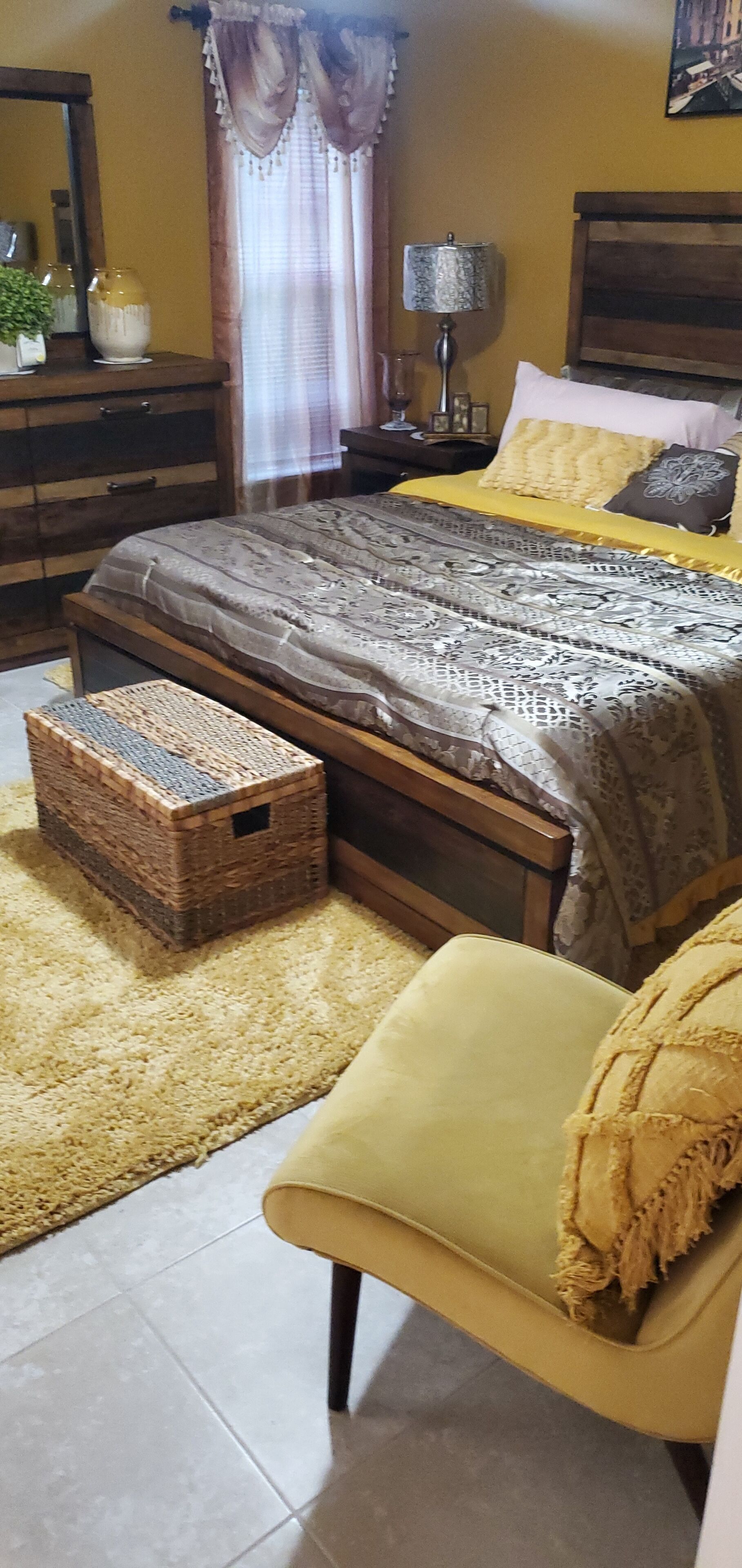 Un dormitorio con cama, mesita de noche, lámpara, cómoda y ventana con cortinas.