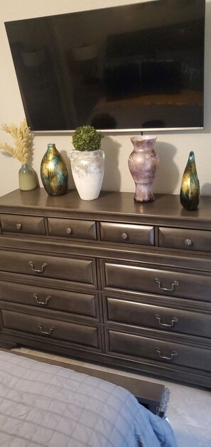 A dark brown dresser with multiple drawers and a flat-screen TV mounted above it.