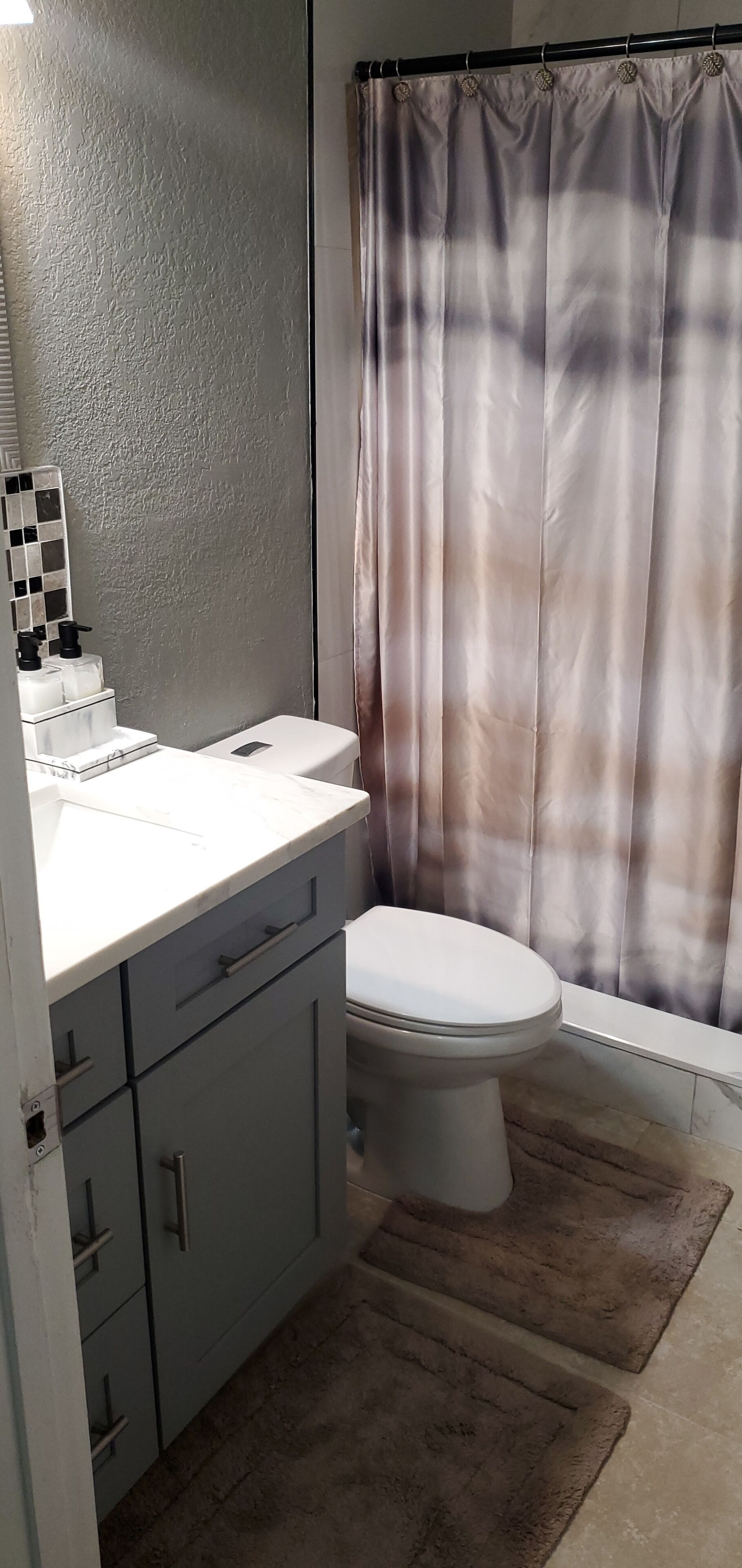 Une salle de bain comprenant des toilettes, un lavabo avec un miroir et un rideau de douche.