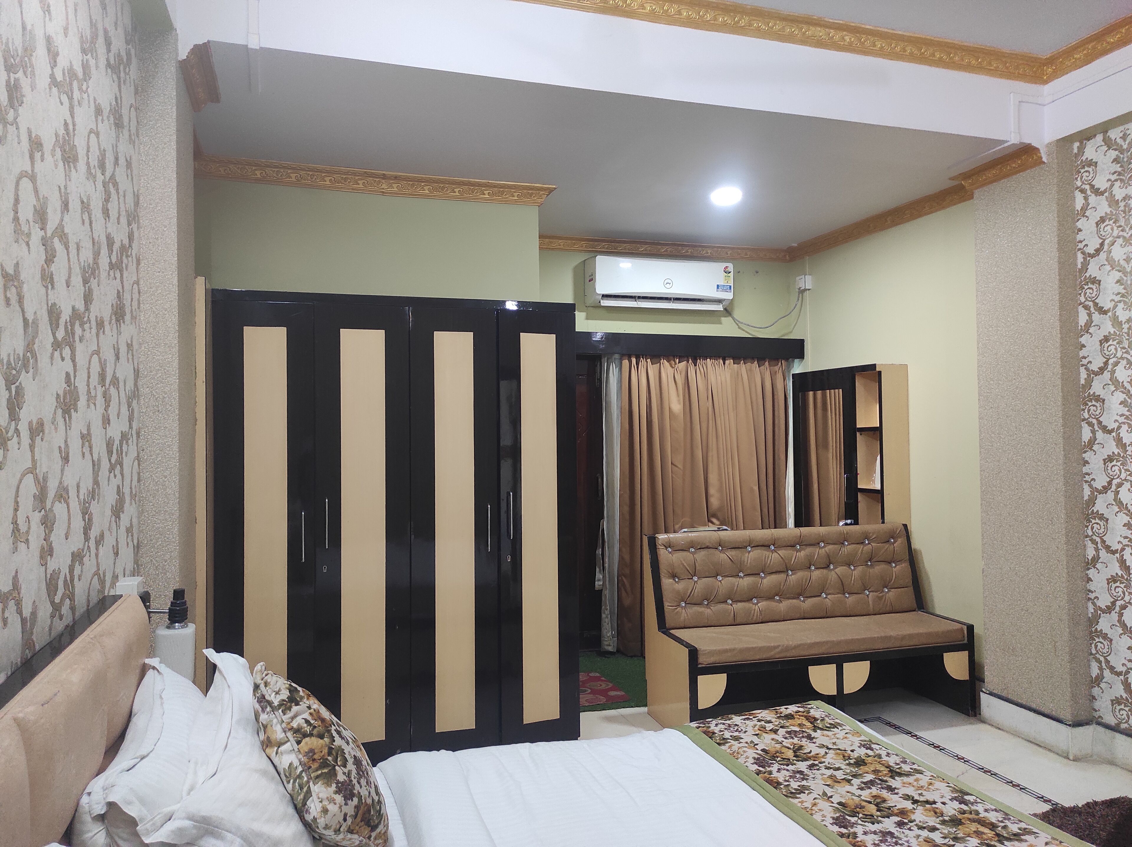 A bedroom with a bed, a sofa, a wardrobe, and a chair.