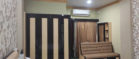 A bedroom with a bed, a sofa, a wardrobe, and a chair.