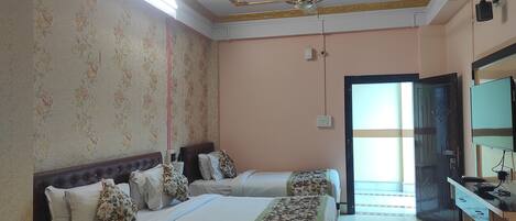 A hotel room with two beds, a ceiling fan, a TV, and a door leading to a balcony.
