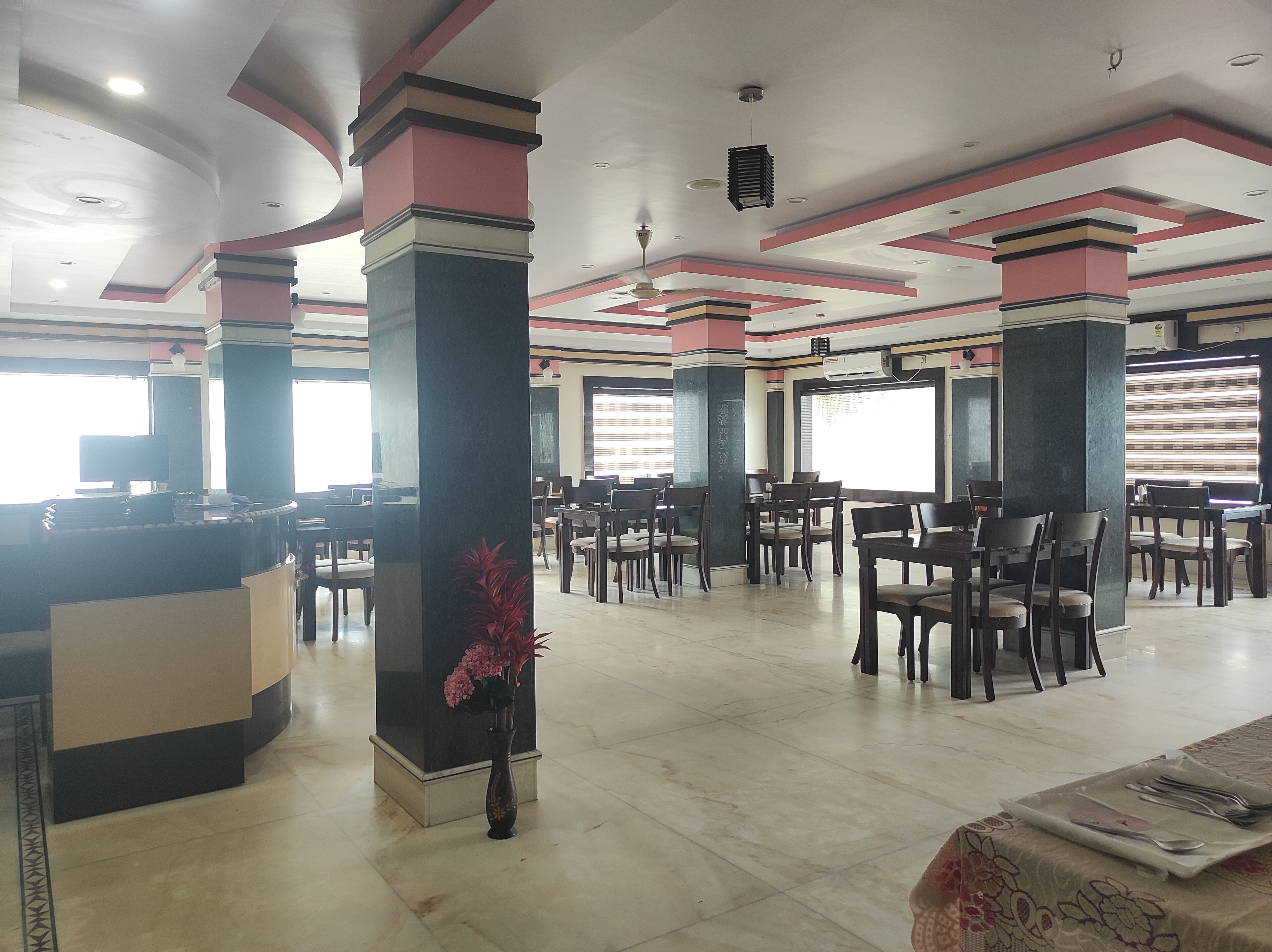 A spacious lobby with a reception desk, multiple seating areas, and a decorative vase with flowers.
