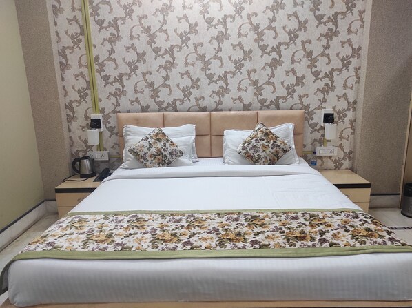 A neatly made bed with floral bedding, a headboard, and two bedside lamps.