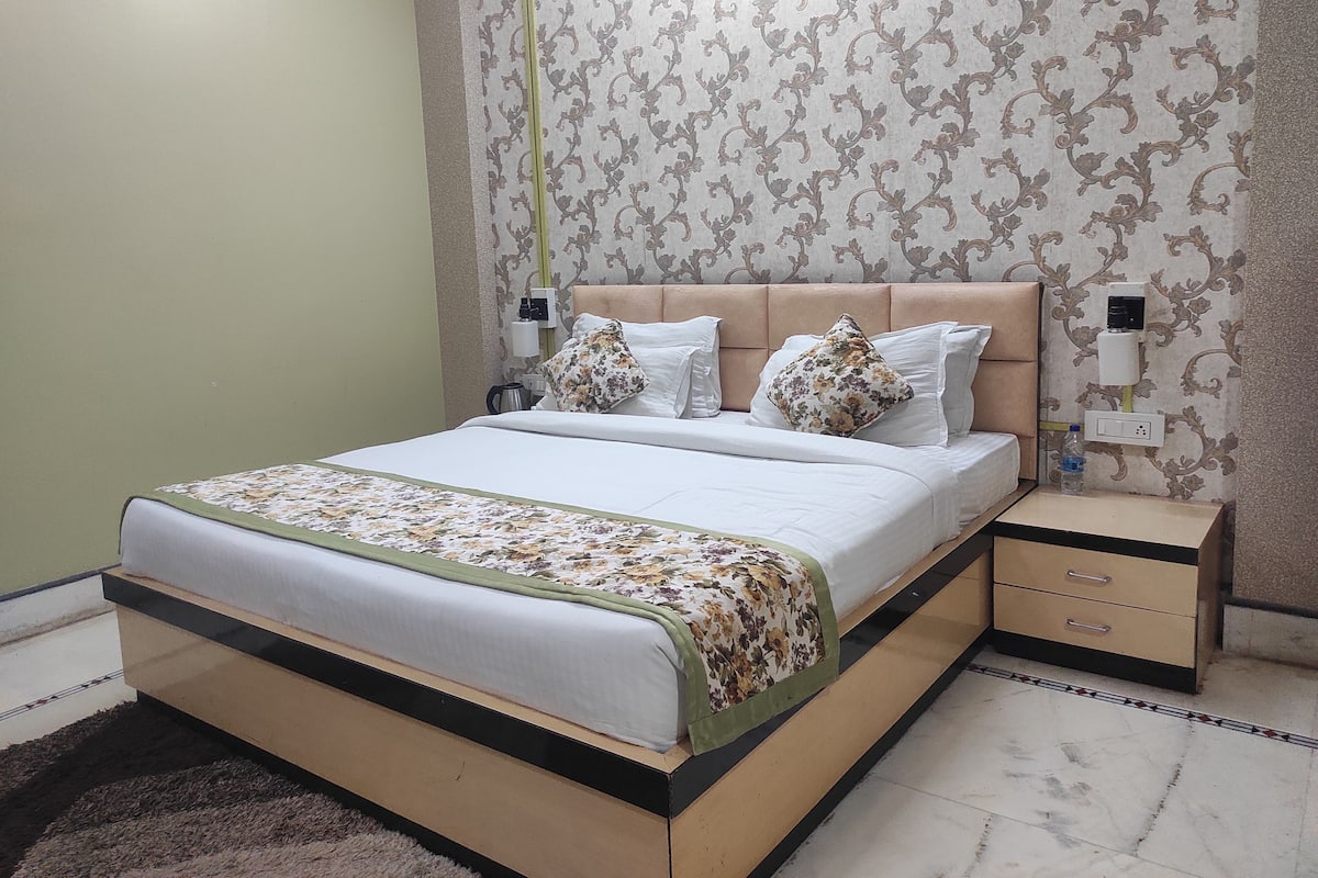 A neatly made bed with floral bedding, a headboard, and bedside tables with lamps.