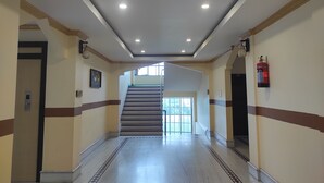 A hallway with a staircase leading to an upper floor, a fire extinguisher on the wall, and a door on the left.