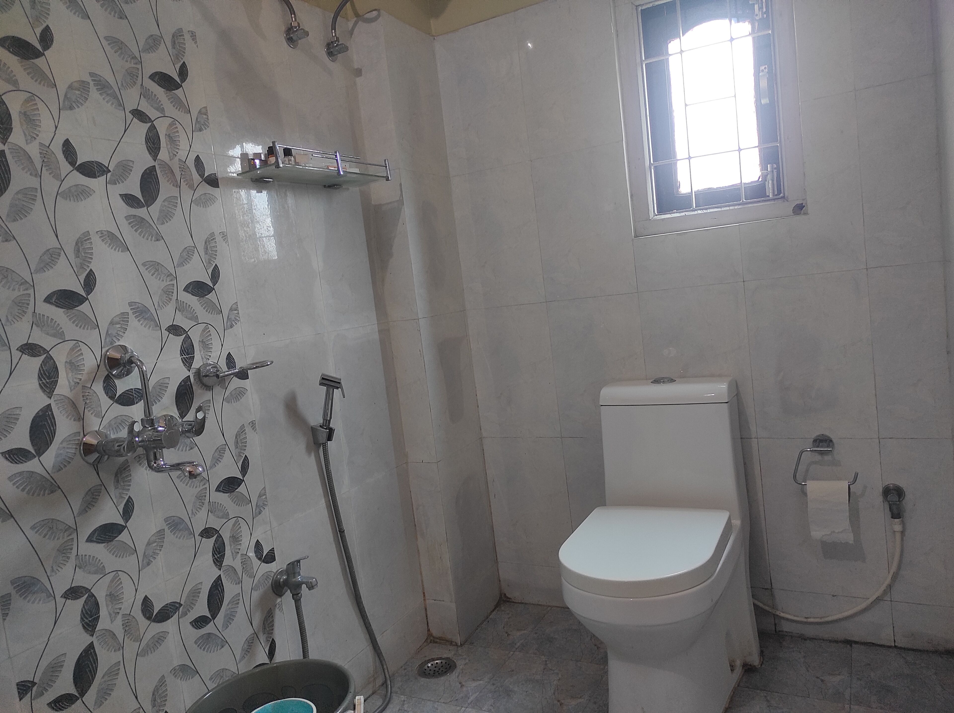A bathroom with a toilet, a shower, and a window.