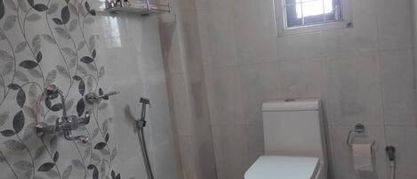 A bathroom with a toilet, a shower, and a window.