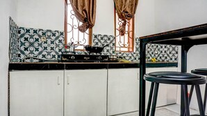 A kitchen with a gas stove, a sink, and a window with curtains. - OYO 90846 Guesthouse Bintaro Asri Syariah (South Tangerang)