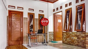 A guesthouse interior with a tiled floor, a wooden door, a desk with a laptop, and a sign indicating the guesthouse name. - OYO 90846 Guesthouse Bintaro Asri Syariah (South Tangerang)