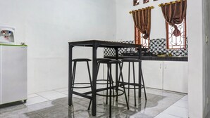 A kitchen with a black table and three stools, a refrigerator, and decorative window valances. - OYO 90846 Guesthouse Bintaro Asri Syariah (South Tangerang)