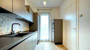 A modern kitchen with a dark countertop, a built-in sink, and a refrigerator. - CaseOspitali - Casa Francesca modernissimo trilo (Pioltello)