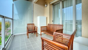 A balcony with two wooden chairs and a sofa, a white refrigerator, and a glass door leading to a terrace. - CaseOspitali - Casa Francesca modernissimo trilo (Pioltello)
