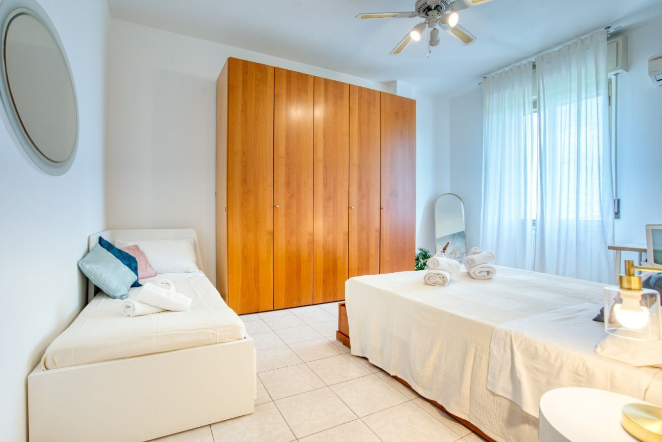 Ein Hotelzimmer mit Bett, einer Couch, einem Holzschrank, einem Spiegel und einem Deckenventilator.