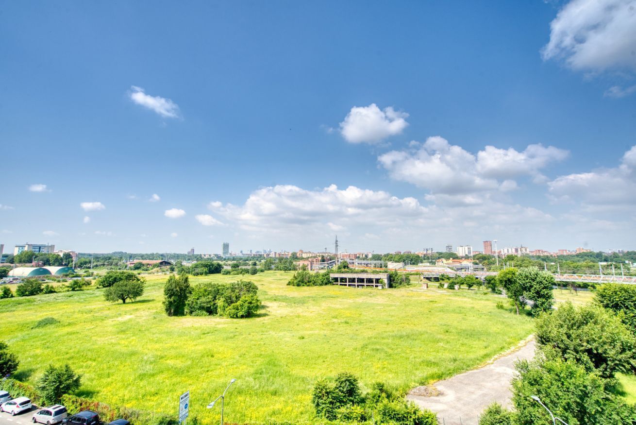 A large open field with a few trees and a building in the distance.