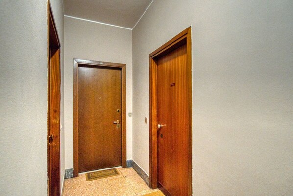 A narrow hallway with two wooden doors, one with a visible handle and another with a lock.
