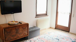 Ein Schlafzimmer mit einem Bett, einem Holzschrank, einem Fernseher und einem Fenster.