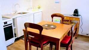 Eine kompakte Küche mit Spüle, Herd und Essbereich mit Holzsesseln und Tisch.