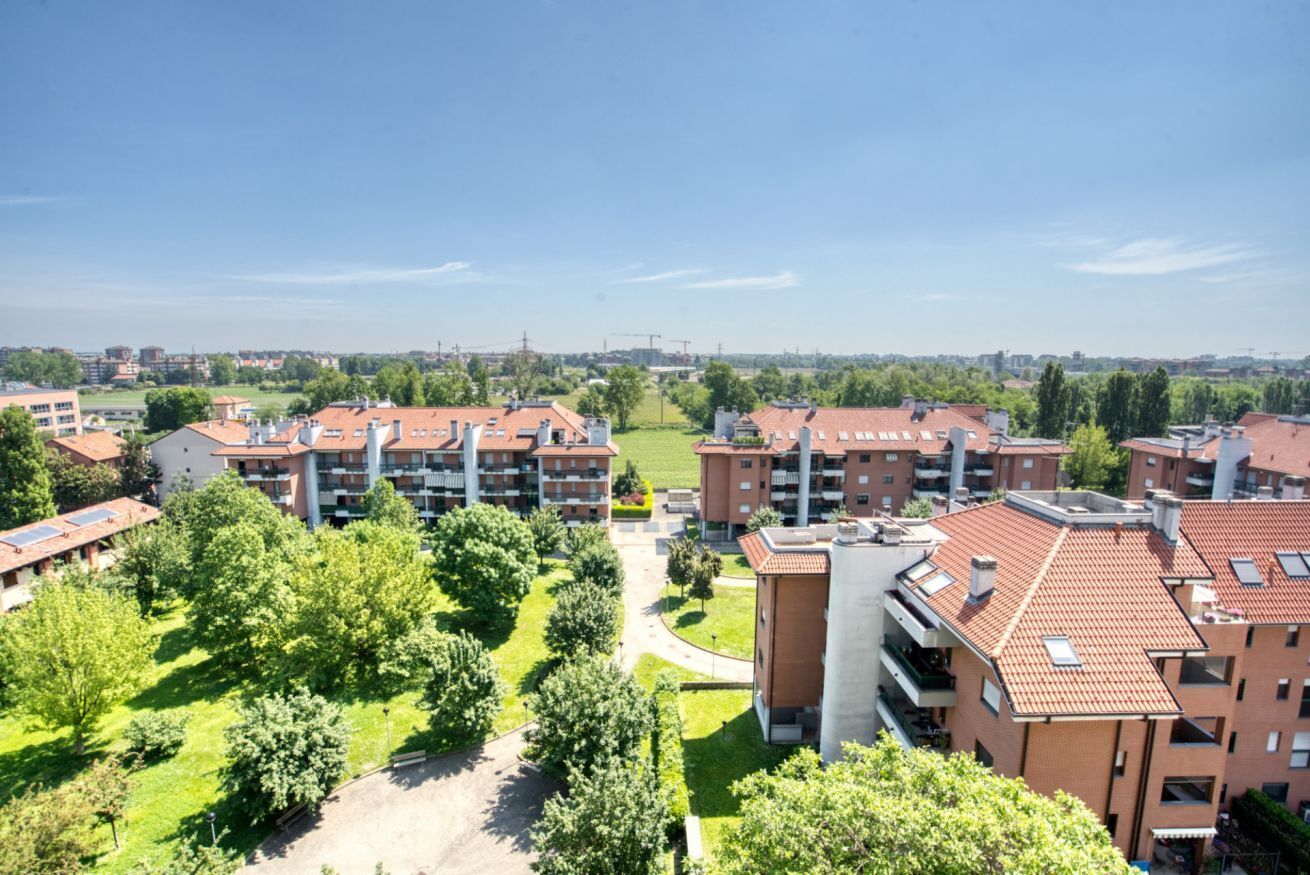 Een woongebied met appartementencomplexen, groene ruimtes en een heldere lucht.