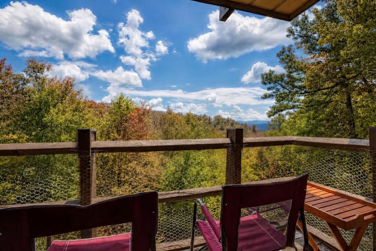 A wooden deck with a view of a forest and mountains.